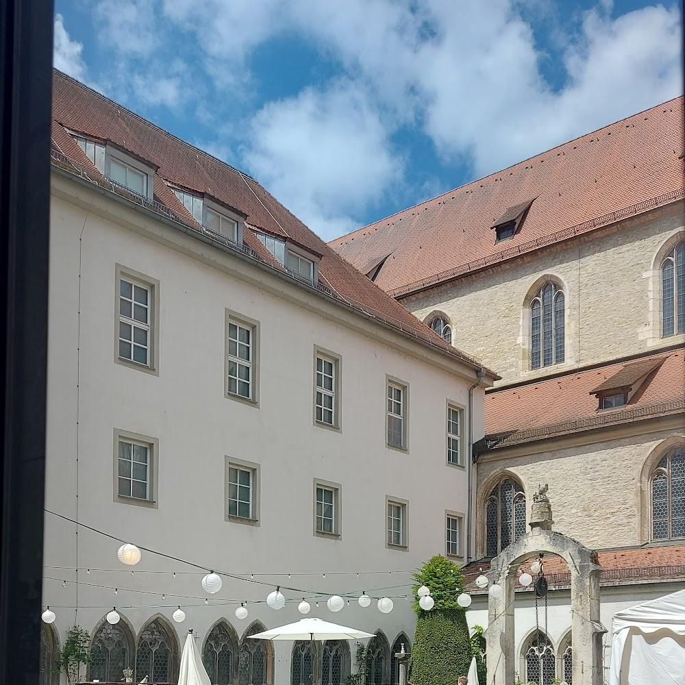 A courtyard with string lights and a white building.  The landmark is the Ulm Minster.